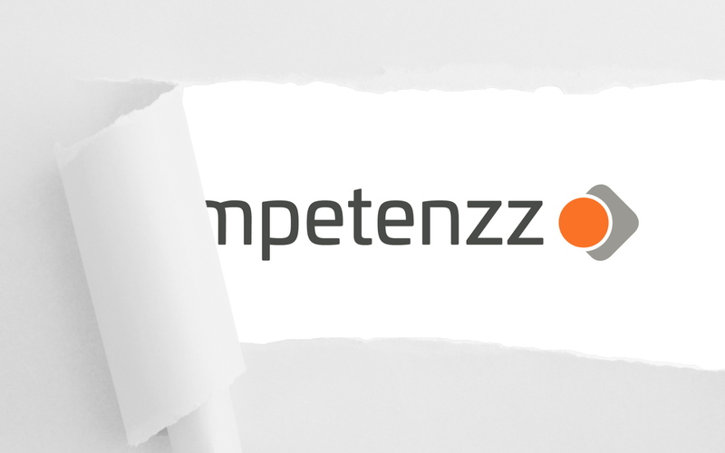 Das Logo von kompetenzz hinter einem aufgerissenen Blatt Papier